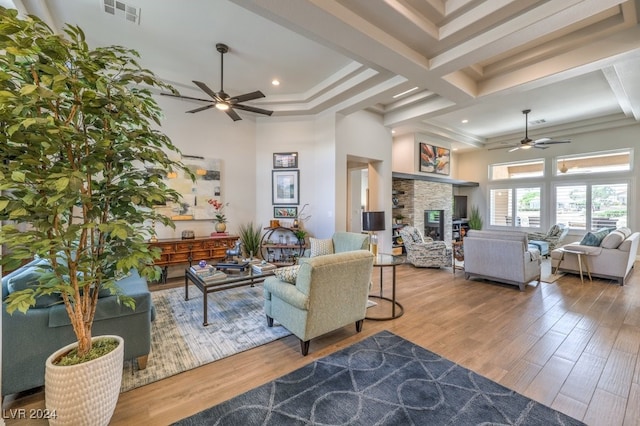 living area with visible vents, a fireplace, a high ceiling, and wood finished floors