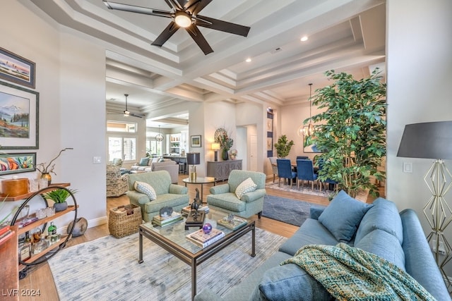 living area featuring a tray ceiling, ornamental molding, ceiling fan, wood finished floors, and baseboards