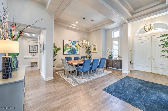 dining area featuring baseboards, a tray ceiling, light wood-style flooring, and a notable chandelier