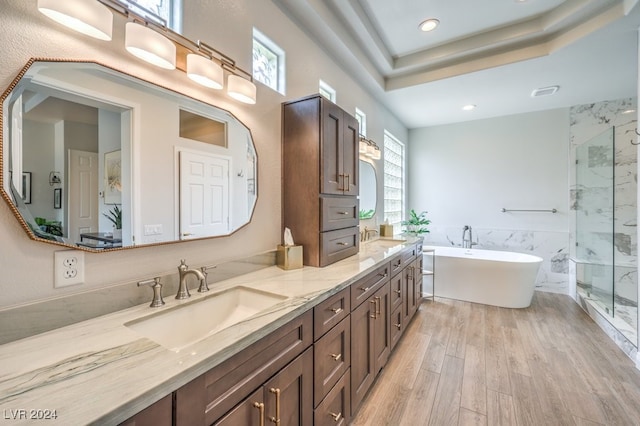 bathroom with double vanity, a marble finish shower, wood finished floors, a freestanding tub, and a sink