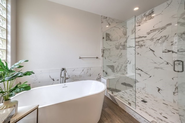 full bath with tile walls, a marble finish shower, recessed lighting, wood finished floors, and a freestanding tub