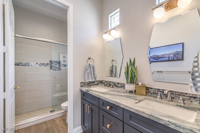 full bath with toilet, a shower stall, a sink, and wood finished floors