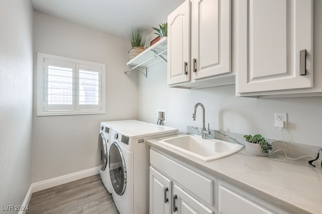 laundry room featuring separate washer and dryer, a sink, baseboards, light wood-type flooring, and cabinet space