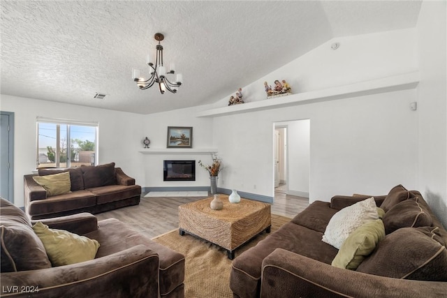 living room featuring light wood-type flooring, vaulted ceiling, a textured ceiling, and an inviting chandelier