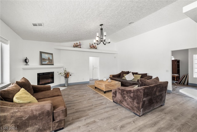 living room with high vaulted ceiling, light wood-type flooring, a textured ceiling, and a chandelier