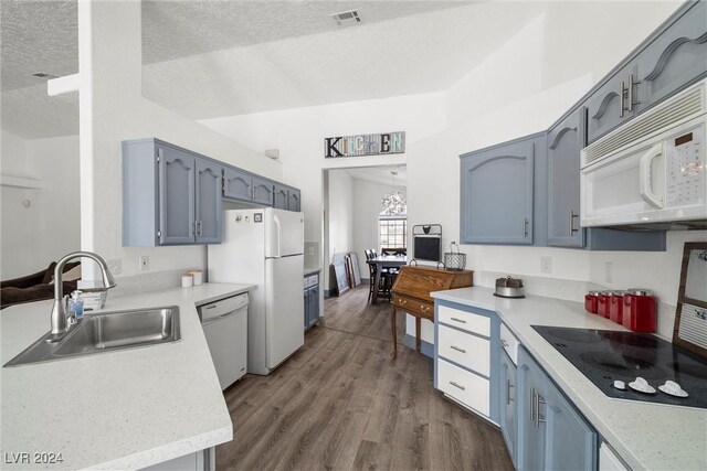 kitchen with white appliances, a textured ceiling, a chandelier, sink, and dark wood-type flooring