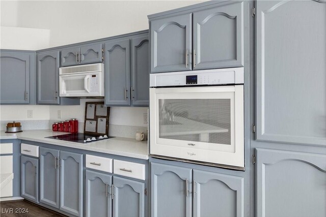 kitchen with gray cabinetry, white appliances, and dark hardwood / wood-style floors