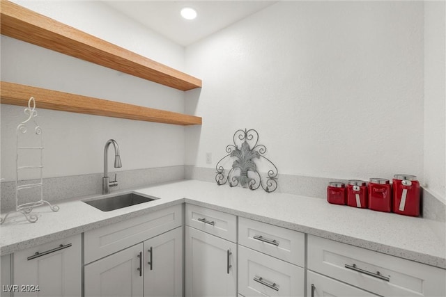 kitchen featuring light stone counters, sink, and white cabinetry