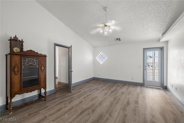 living room featuring ceiling fan, vaulted ceiling, a textured ceiling, and hardwood / wood-style floors