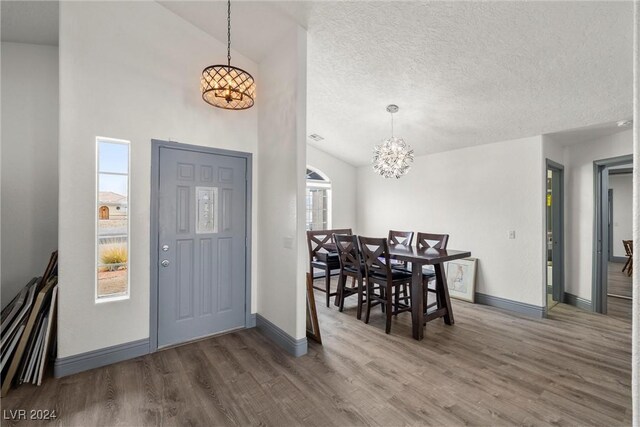 foyer featuring a textured ceiling, high vaulted ceiling, a chandelier, and hardwood / wood-style floors