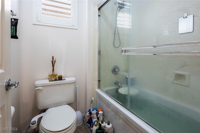 bathroom with enclosed tub / shower combo and toilet