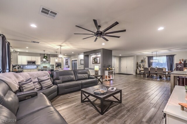 living room with ceiling fan with notable chandelier and hardwood / wood-style floors