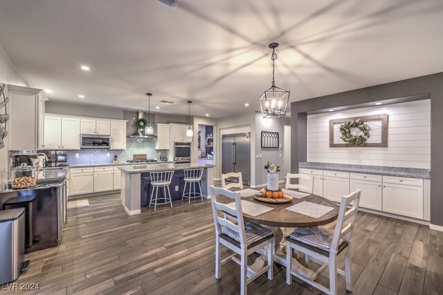 dining area with sink, dark hardwood / wood-style floors, and an inviting chandelier