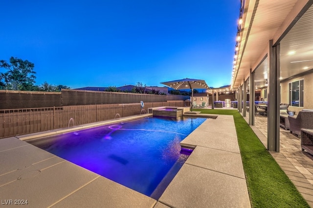 pool at dusk featuring a patio and pool water feature