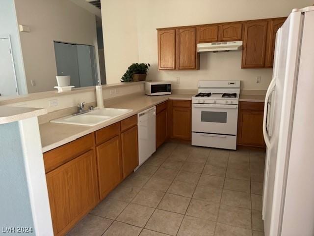 kitchen with sink, white appliances, kitchen peninsula, and light tile patterned floors