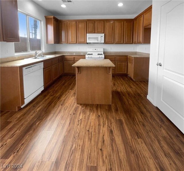 kitchen with white appliances, sink, dark hardwood / wood-style flooring, and a kitchen island