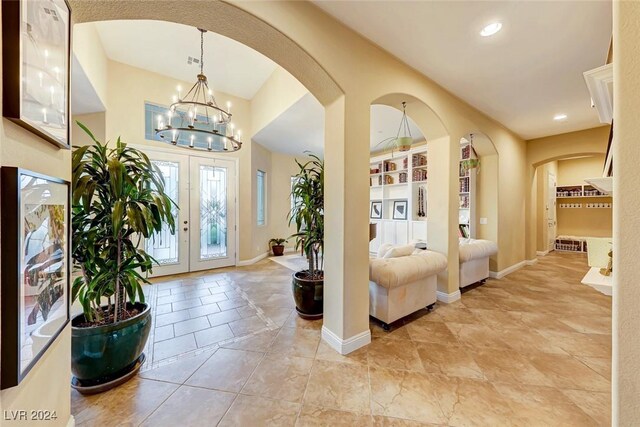 foyer with french doors, light tile patterned floors, and a chandelier