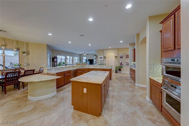 kitchen with kitchen peninsula, light tile patterned floors, a kitchen island, and sink