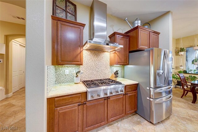 kitchen with stainless steel appliances, light stone countertops, light tile patterned floors, decorative backsplash, and wall chimney range hood