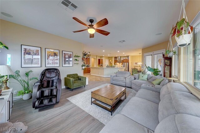 living room featuring light wood-type flooring, ceiling fan, and a healthy amount of sunlight