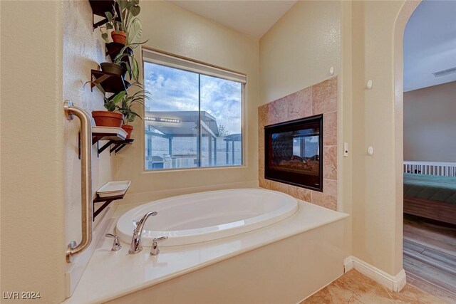 bathroom featuring tile patterned floors, a tub, and a tile fireplace