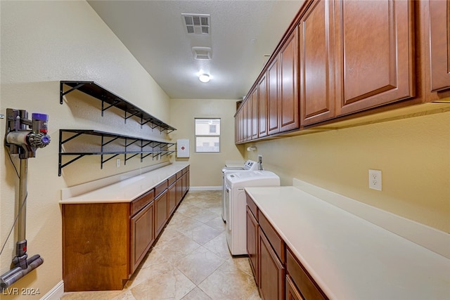 laundry area with washing machine and dryer, light tile patterned flooring, and cabinets