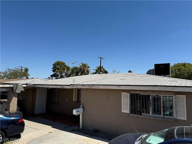 view of property exterior with a patio area, a shingled roof, and stucco siding