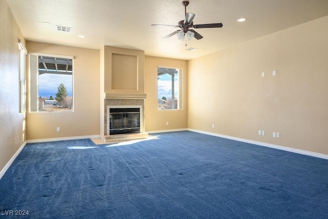 unfurnished living room featuring ceiling fan, a fireplace, and dark carpet