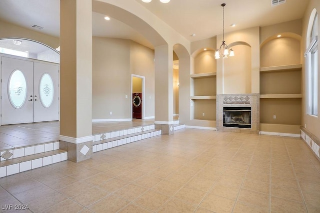 tiled entryway featuring a high ceiling, a tile fireplace, washer / dryer, and a notable chandelier