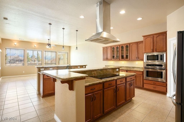 kitchen featuring a kitchen island, pendant lighting, island exhaust hood, light stone counters, and stainless steel appliances