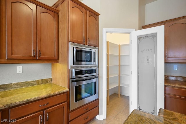 kitchen featuring stainless steel appliances, light stone countertops, and light tile patterned floors