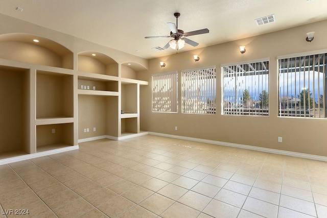 tiled spare room with built in shelves and ceiling fan