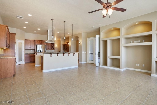 kitchen with island range hood, decorative light fixtures, stainless steel fridge with ice dispenser, a center island with sink, and built in shelves