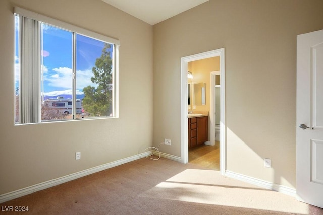 unfurnished bedroom featuring ensuite bath and light carpet