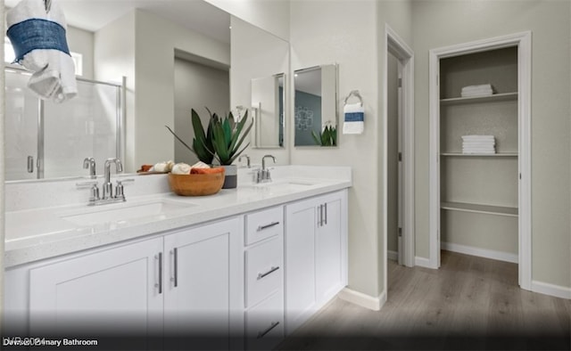 bathroom with hardwood / wood-style flooring, vanity, built in shelves, and a shower with door