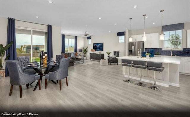 dining space with sink, ceiling fan, and light wood-type flooring