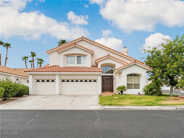 mediterranean / spanish-style house with concrete driveway, a tile roof, a chimney, and stucco siding