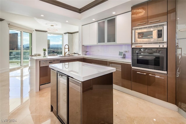 kitchen with crown molding, appliances with stainless steel finishes, a kitchen island, sink, and white cabinetry