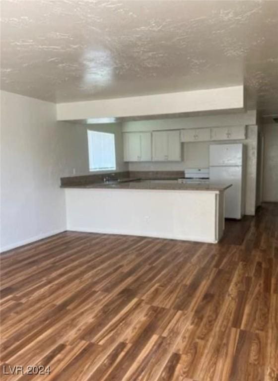 kitchen featuring white refrigerator, dark hardwood / wood-style floors, a textured ceiling, and kitchen peninsula