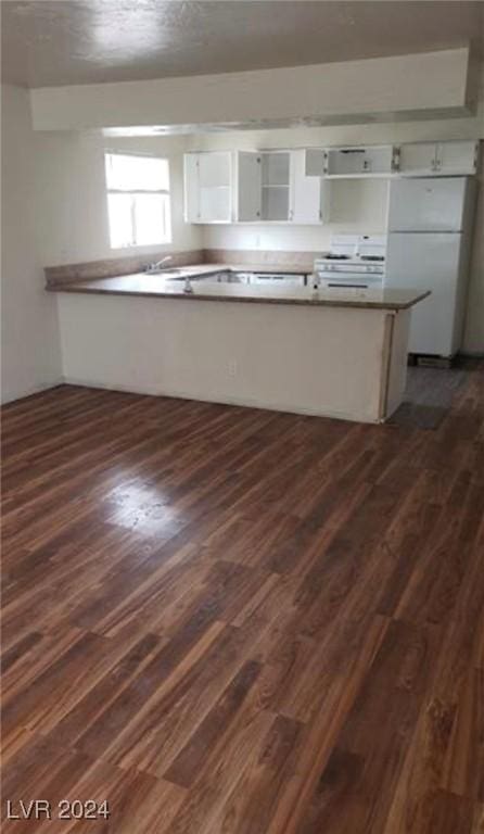 kitchen featuring white fridge, white cabinets, dark hardwood / wood-style flooring, and kitchen peninsula