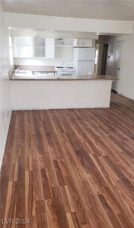 kitchen with white fridge, dark wood-type flooring, white cabinets, and kitchen peninsula