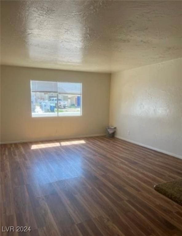 spare room featuring dark hardwood / wood-style floors and a textured ceiling