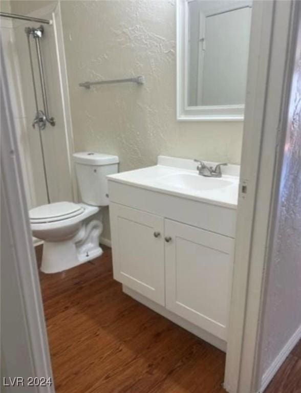 bathroom with vanity, wood-type flooring, toilet, and a shower