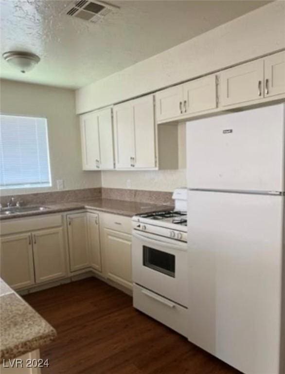 kitchen featuring sink, white appliances, white cabinetry, a textured ceiling, and dark hardwood / wood-style flooring