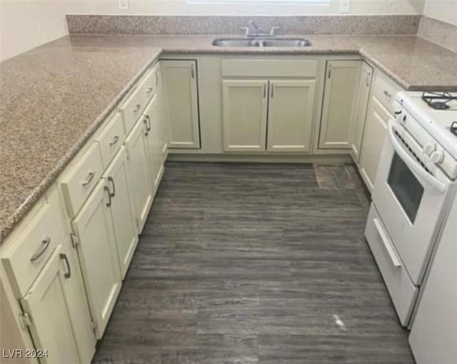 kitchen featuring sink, white range with gas stovetop, cream cabinets, light stone countertops, and dark hardwood / wood-style flooring