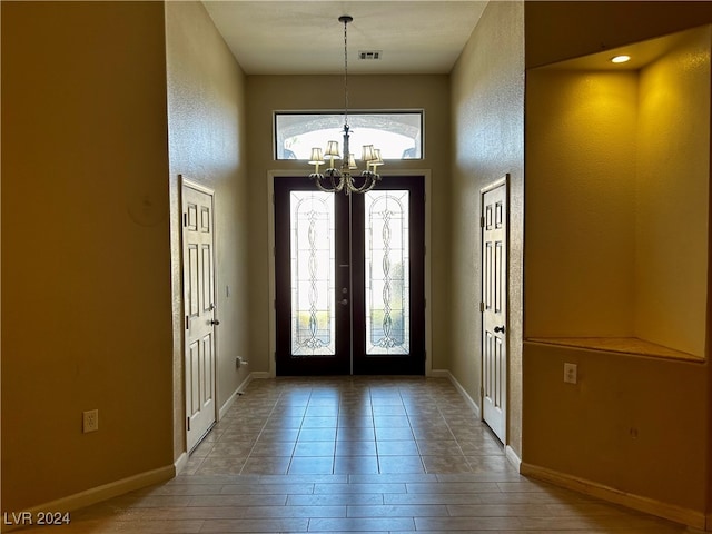 foyer entrance featuring french doors, an inviting chandelier, and hardwood / wood-style floors