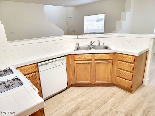 kitchen with tile counters, sink, light hardwood / wood-style flooring, and white dishwasher