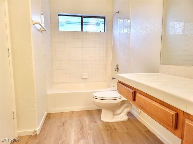 full bathroom featuring vanity, toilet, hardwood / wood-style floors, and tiled shower / bath