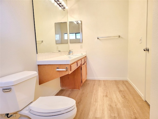 bathroom with toilet, vanity, and wood-type flooring