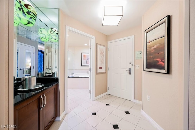 interior space featuring a garden tub, tile patterned flooring, baseboards, and vanity